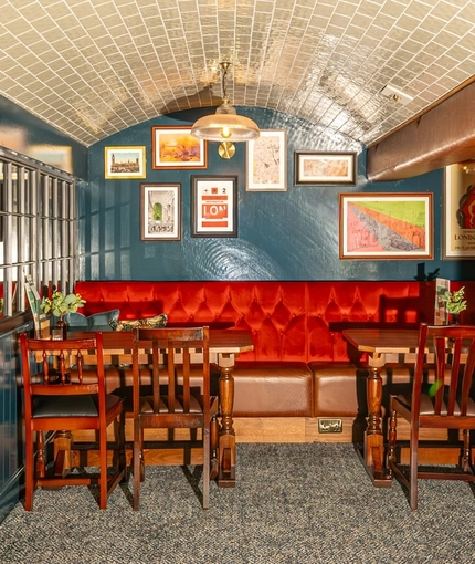 The interior restaurant booth seating area of the Monument, beneath large tiled archways and with framed artwork on the wall.