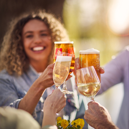 An exterior image showing 4 people sat with a selection of alcoholic drinks celebrating with a cheers at a Chef & Brewer venue.