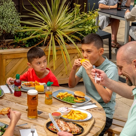 A family seated at an outdoor table in a beer garden, enjoying a meal.