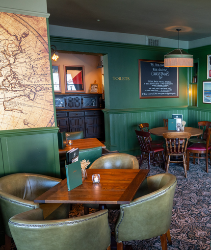 An image of the interior restaurant seating area with tables, chairs, cushioned seating and brick with beams feature wall at The Spice Island.