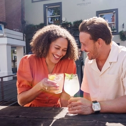 An exterior image of people sat within a beer garden seating area enjoying drinks during the Q3 Happy Hour Event.