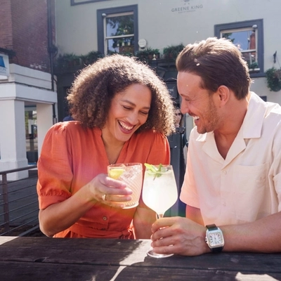 An exterior image of people sat within a beer garden seating area enjoying drinks during the Q3 Happy Hour Event.