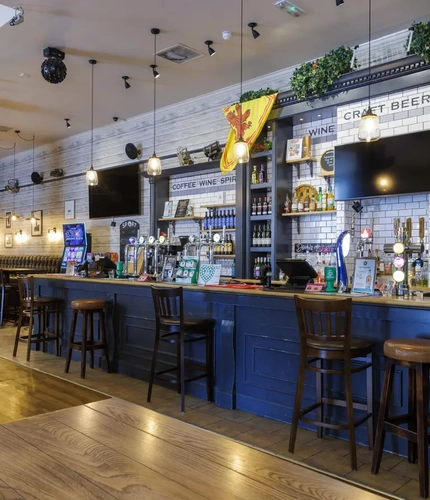 Interior dining area of a pub with TVs and a bar.