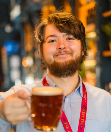 A team member holding up a pint of beer.