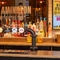 A close up view of the bar inside The Amington in Tamworth, with bottles of alcoholic spirits on a wooden shelf behind the counter, and a TV on the wall.