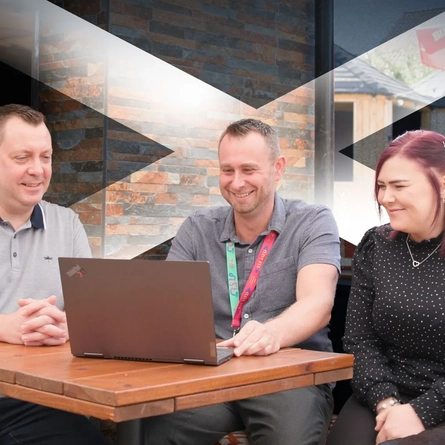 3 Staff member sitting round a laptop at a Belhaven venue.