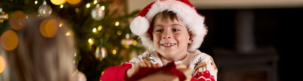 An image of an adult and child exchanging a gift while enjoying fruit juice and dishes from the Breakfast with Santa menu at Chef & Brewer venues.
