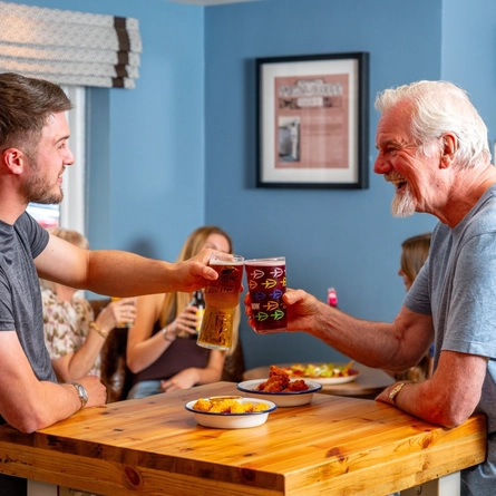 An image of a group of people enjoying nacho sharer and snack dishes with various drinks within the interior of a Hungry Horse venue.