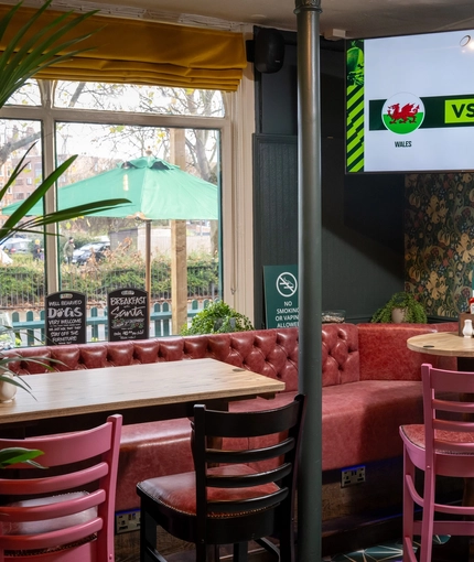 An interior restaurant seating area at The Grosvenor, with an upholstered booth seat, and a TV on the wall in the corner.