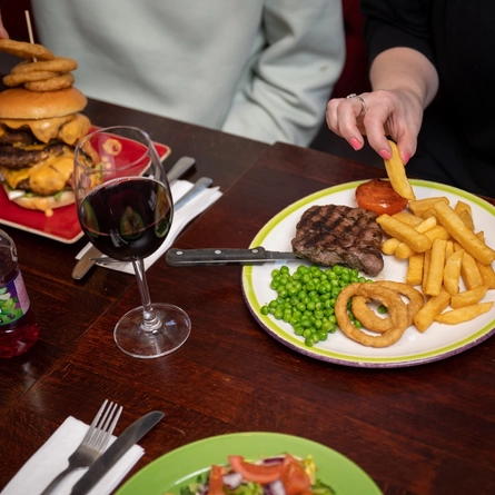 plates of food and drinks sitting on a wooden table of a pub