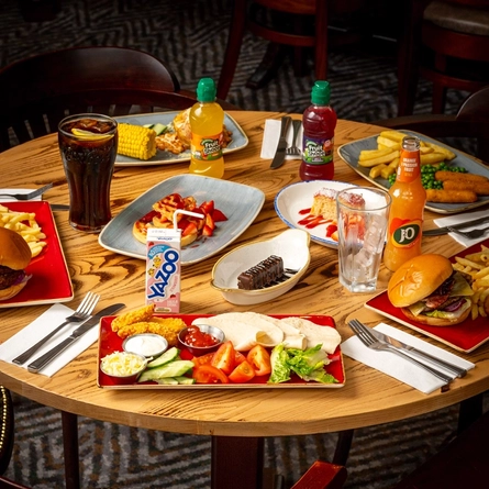 An indoor table set up with several main meals, desserts and drinks.