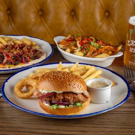 A selection of June Burger of the Month dishes on an indoor table with a pint of  Level Head.