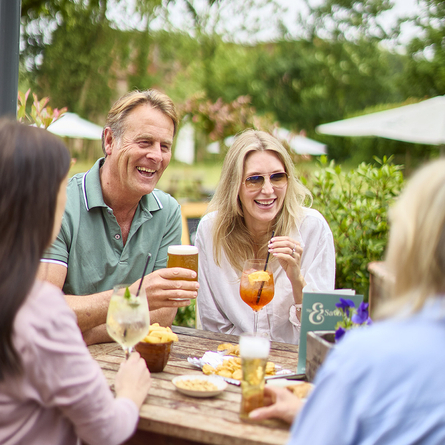 An exterior shot of people enjoying drinks & nibbles in a beer garden/outdoor seating area for a summer promotion at a Chef & Brewer Venue.