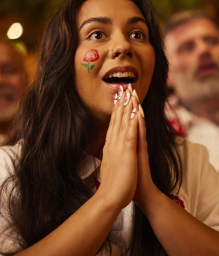 An image of a woman wearing a sport team shirt, watching a sporting event.