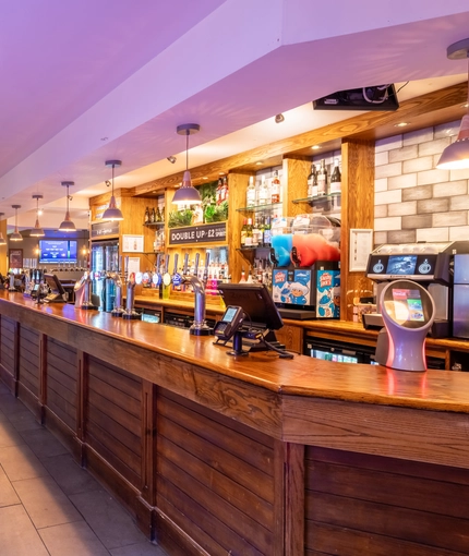 Interior bar area and dining area of a pub with a few gambling machines.