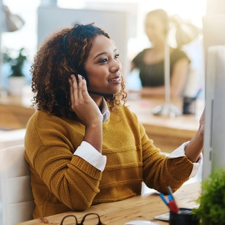 A woman sitting at a desk with a headset on.