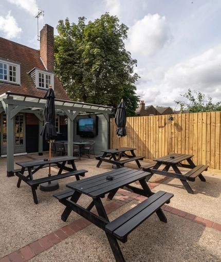 An image of the exterior beer garden seating area with partial covered section and outdoor TV at The Old Red Lion.