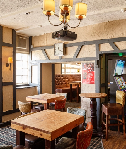 Interior dining area of a pub with a TV, a fireplace, a pool table and a gambling machine.