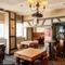 Interior dining area of a pub with a TV, a fireplace, a pool table and a gambling machine.