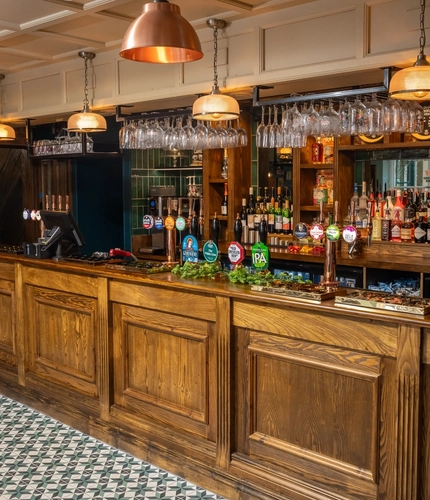 The wood panelled bar inside The White Lion, with wine glasses hanging in racks above the counter.