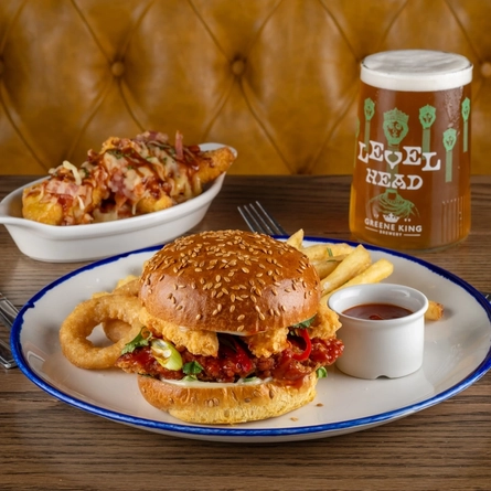 Plates of food and a pint of Level Head on a table.