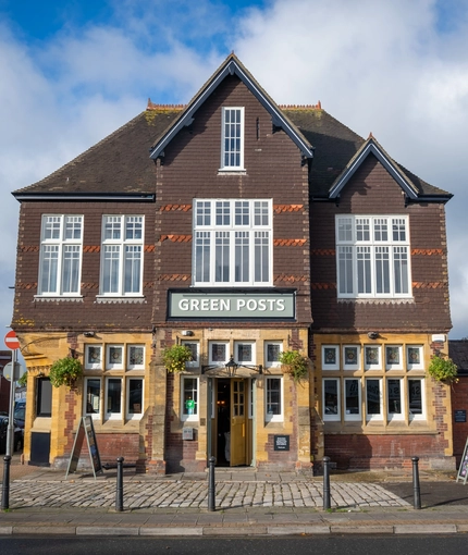 The exterior facade and signage of the Green Posts in Portsmouth, with hanging flowers baskets on the wall.