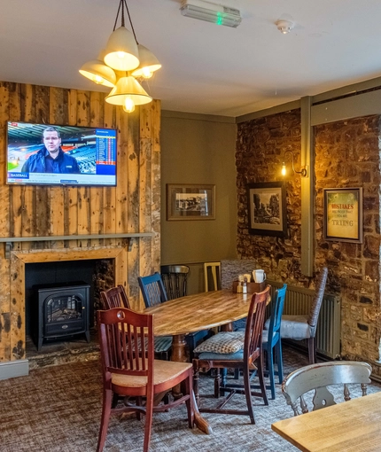 Interior dining area of a pub with a TV and a fireplace.