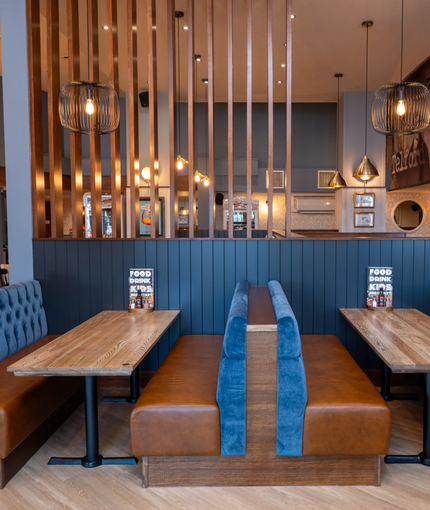 An interior restaurant booth seating area at The Wrekin Giant, with framed artwork and a TV on the wall.
