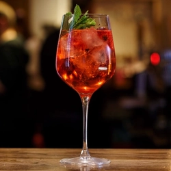 A cocktail in stemmed goblet glassware on a bar.