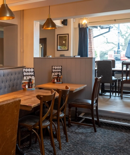 An interior restaurant seating area at The Vine Inn, with a long, upholstered booth seat, and framed artwork on the walls.