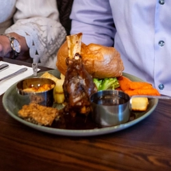 An image of people enjoying a Sunday Roast and various drinks within the interior restaurant seating area at a Community Pubs with Food venue.