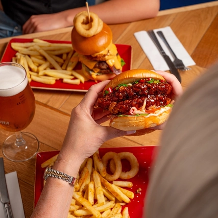 A close up image of 2 burgers and various drinks sat on a table within the interior restaurant and seating area at a Hungry Horse venue.