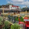 The exterior beer garden seating area at The Heron in Havant; with wooden picnic tables, shade umbrellas, and string lights overhead.