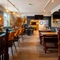 The interior restaurant seating area at The Talbot in Worcester; with a pool table, an illuminated dartboard, TVs on the walls, and a wooden staircase leading to the upper floor.