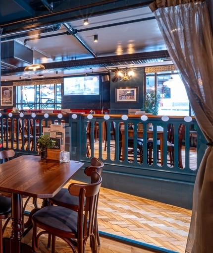 The interior restaurant seating area of the Monument, with wooden tables and chairs, and parquet floor.