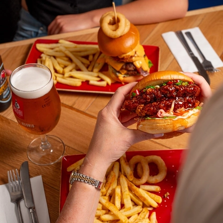 A close up image of 2 burgers and various drinks sat on a table within the interior restaurant and seating area at a Hungry Horse venue.