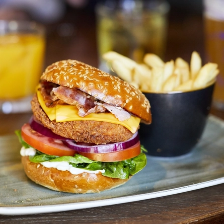 A plated burger and chips on an indoor table.