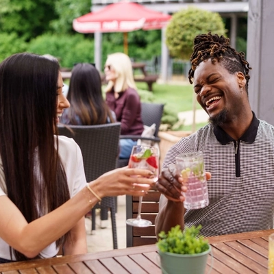 A mixed group of people sat in a beer garden, enjoying cocktails.