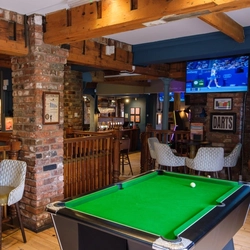 The interior bar and restaurant seating area with TV screens and pool table at The Guild.