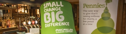 A life-size Macmillan charity pot in front of a bar.