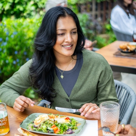 An image of people enjoying various food and drinks within the exterior beer garden seating area at a Community Pubs with Food venue.