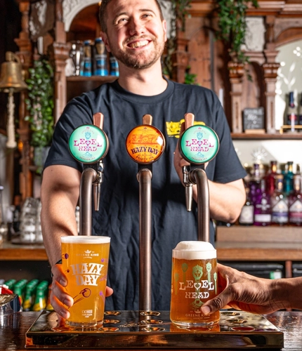 A pint of Level Head and Hazy Day being placed down by a smiling bartender.
