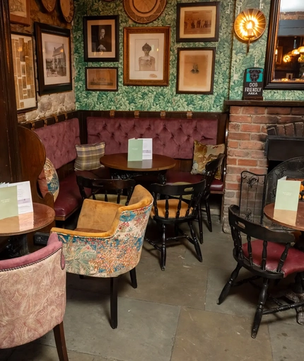 Some tables and a fireplace in a seating area of The Rockingham Arms.