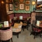 Some tables and a fireplace in a seating area of The Rockingham Arms.