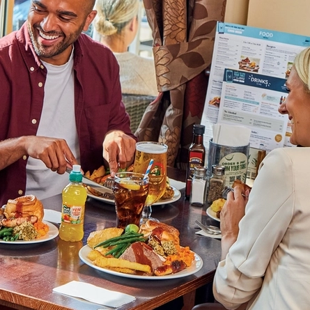 family sitting round a table in a restaurant eating a roast dinner