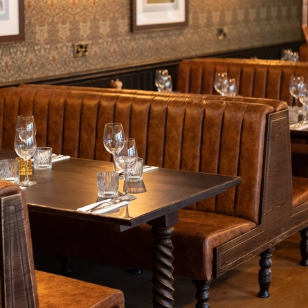 A seating area with a table set with wine glasses and lowball glasses and cutlery