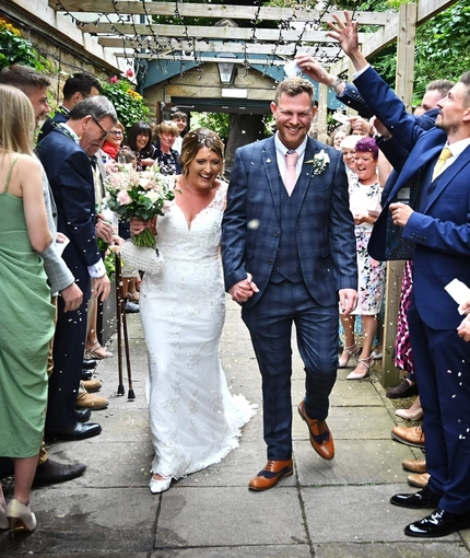 A bride and groom walking through an archway of guests.