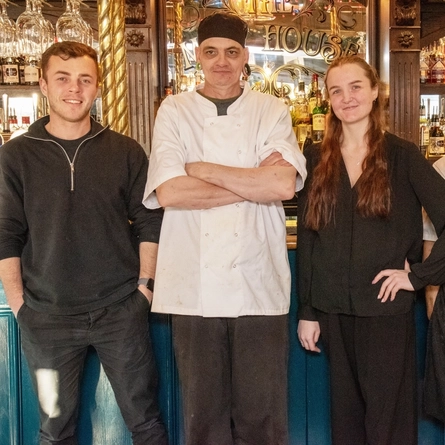 Four staff members standing in front of a bar.