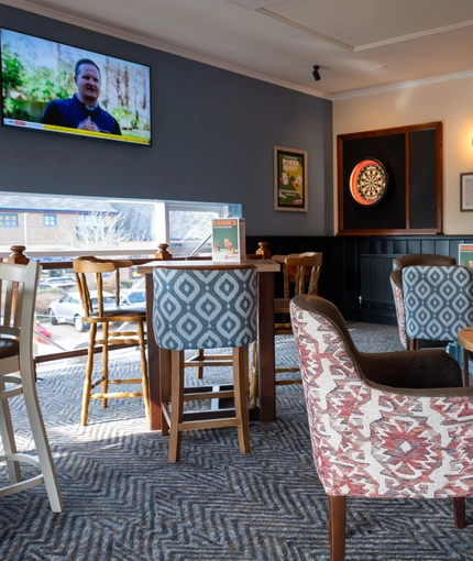 The interior restaurant and seating area with TV and dart board at The Woodlands.