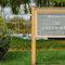 An exterior sign saying "Welcome to The Green Man", which stands on a patch of grass, surrounded by bushes.